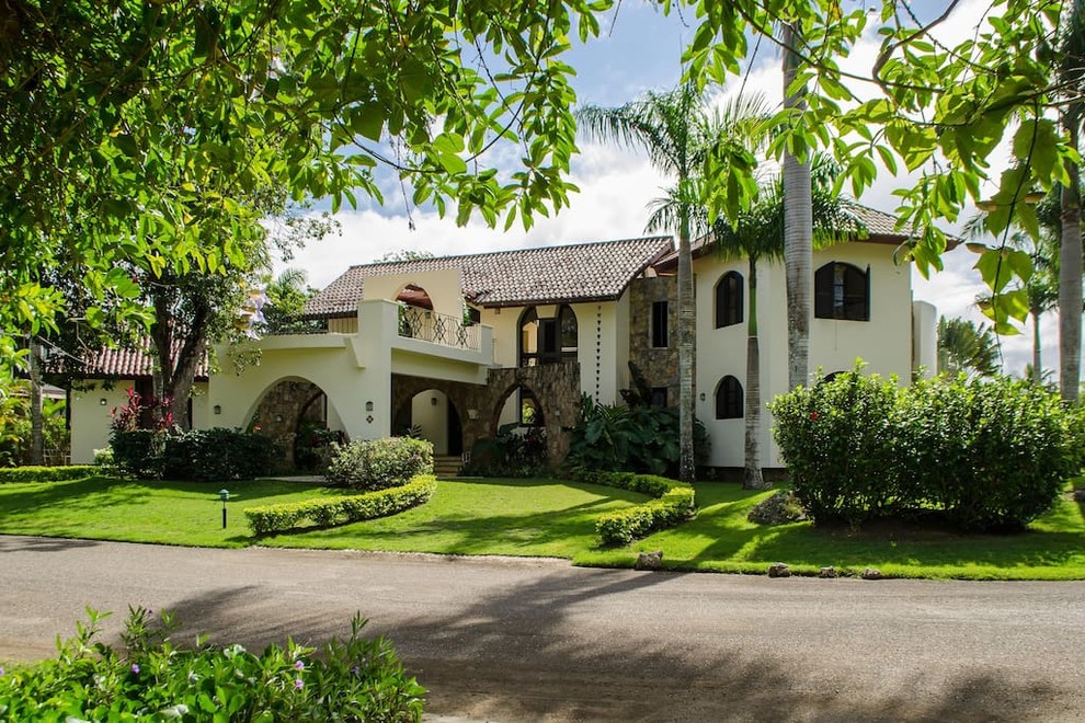 Diseño de fachada de casa blanca tropical extra grande de dos plantas con revestimiento de estuco, tejado a dos aguas y tejado de teja de barro