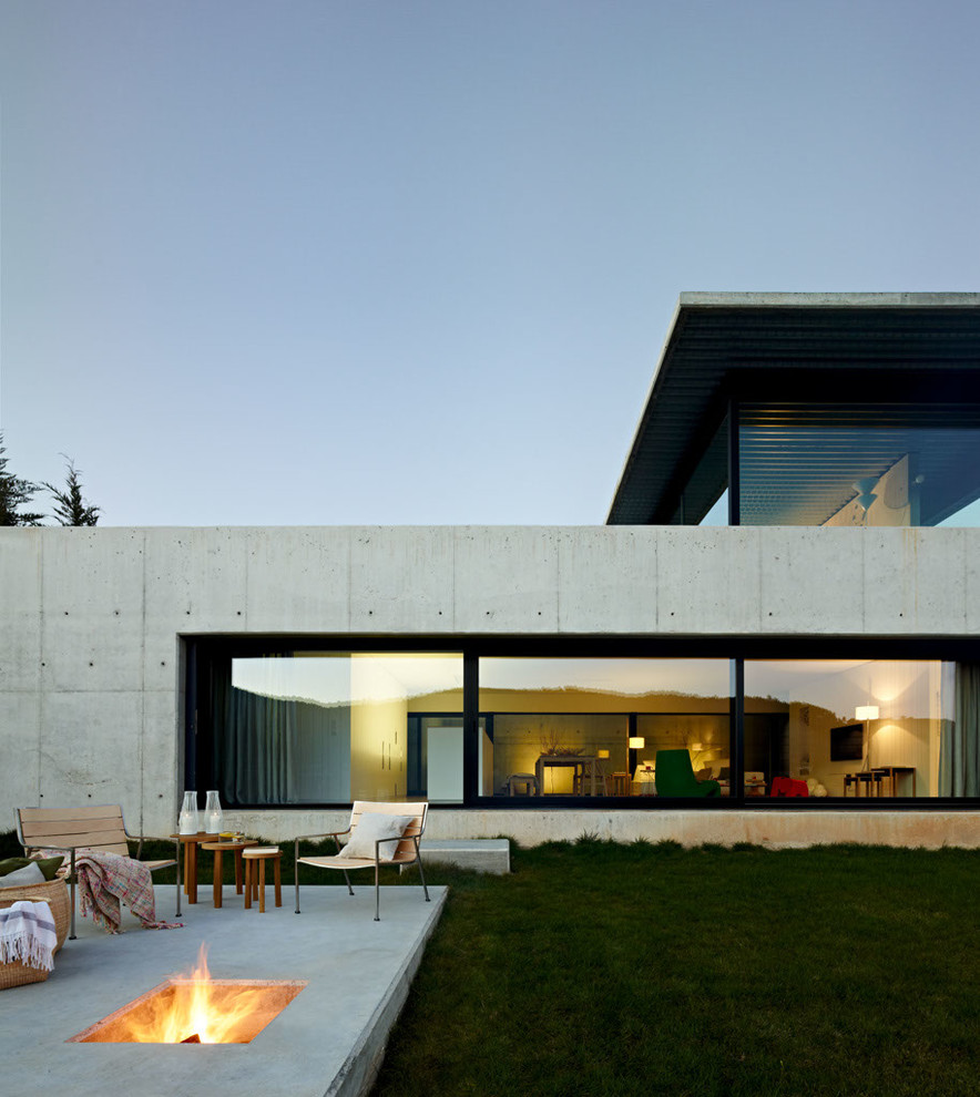 Réalisation d'une grande façade de maison grise design en béton à niveaux décalés avec un toit plat.