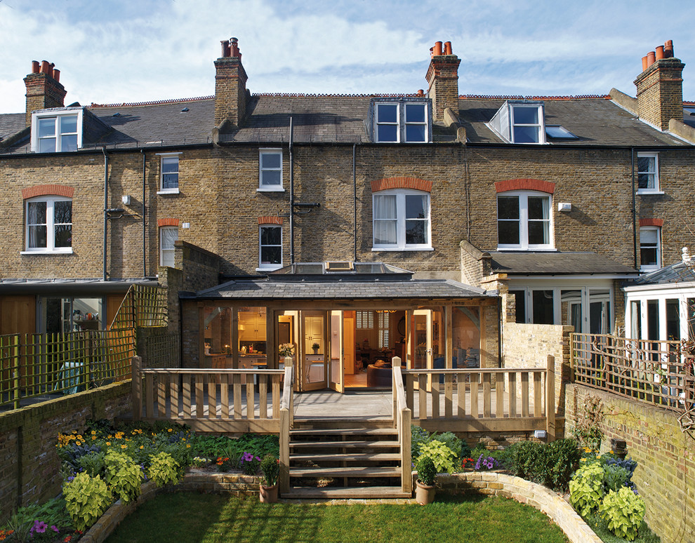 Photo of a brown traditional two floor rear extension in London with stone cladding and a pitched roof.
