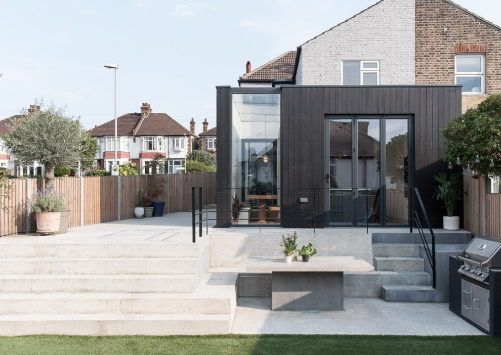 Mittelgroßes, Einstöckiges Modernes Haus mit schwarzer Fassadenfarbe, Flachdach und Misch-Dachdeckung in London