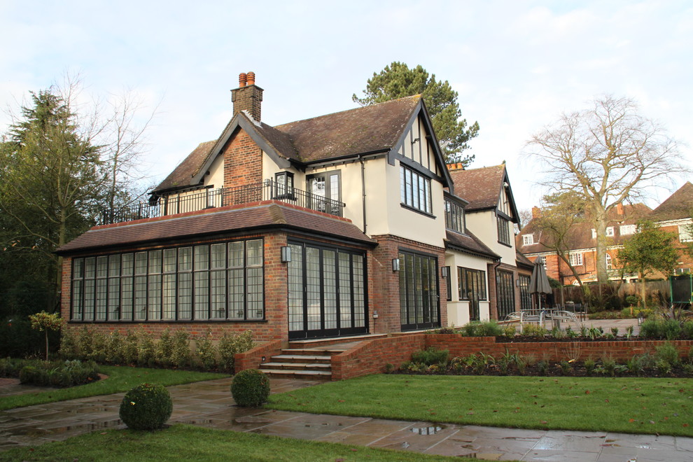 Cette image montre une grande façade de maison beige traditionnelle à un étage avec un revêtement mixte.