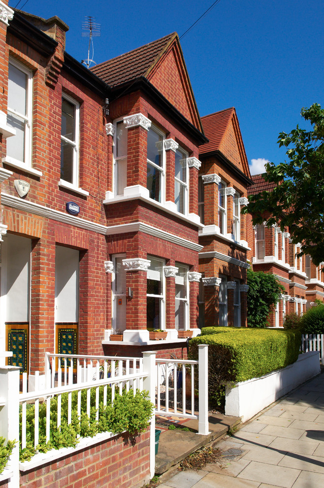 This is an example of a medium sized bohemian brick house exterior in London with three floors and a mansard roof.