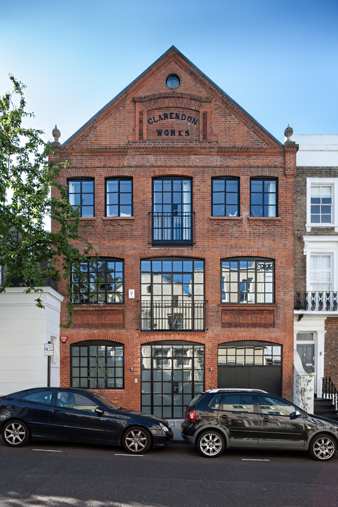 Large and red industrial brick detached house in London with three floors and a pitched roof.