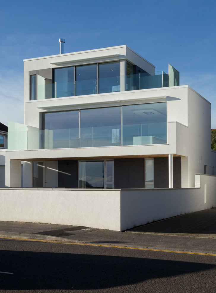 Diseño de fachada de casa blanca actual de tamaño medio de tres plantas con revestimientos combinados y tejado plano