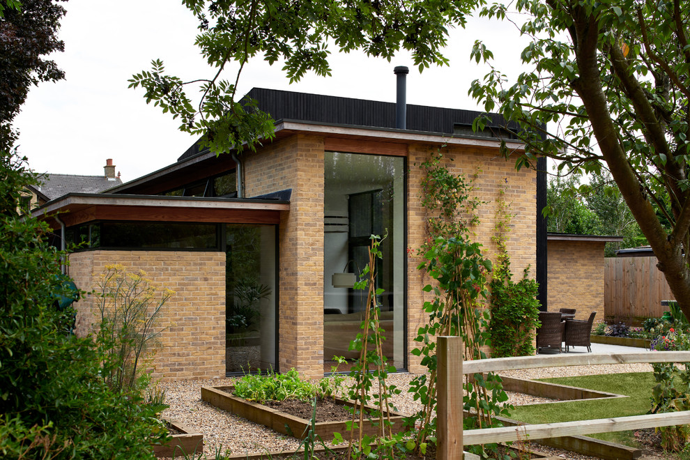 Aménagement d'une façade de maison noire contemporaine en bois de taille moyenne et à un étage avec un toit plat et un toit végétal.