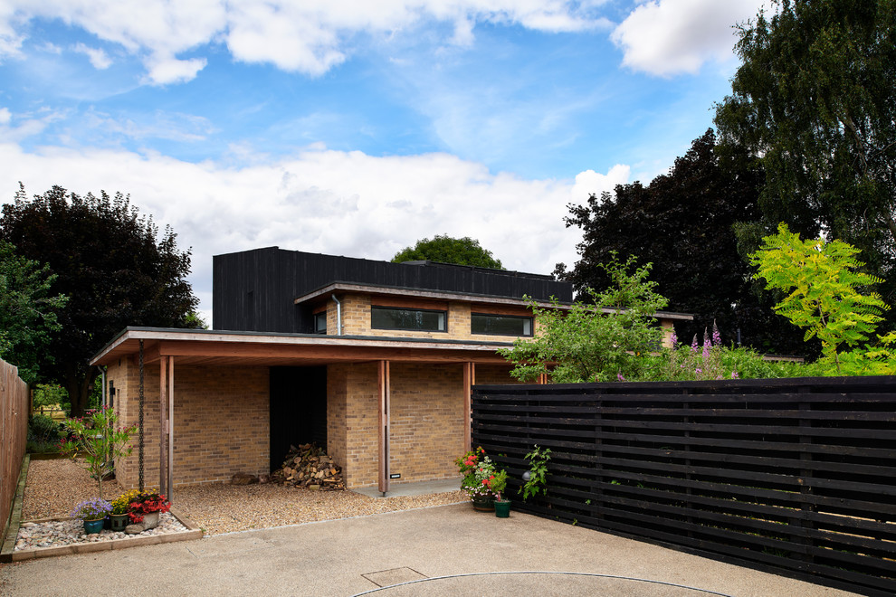 Стильный дизайн: двухэтажный, деревянный, черный частный загородный дом среднего размера в современном стиле с плоской крышей и зеленой крышей - последний тренд