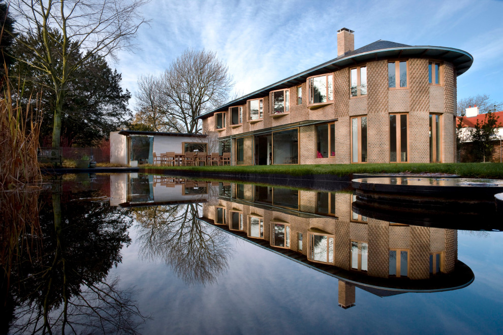 Inspiration for an expansive and brown contemporary two floor detached house in London with mixed cladding, a half-hip roof and a black roof.