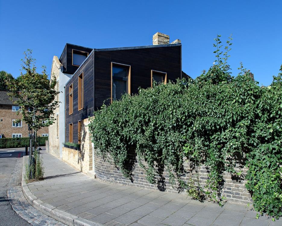 Réalisation d'une façade de maison noire design en bois de taille moyenne et à un étage.