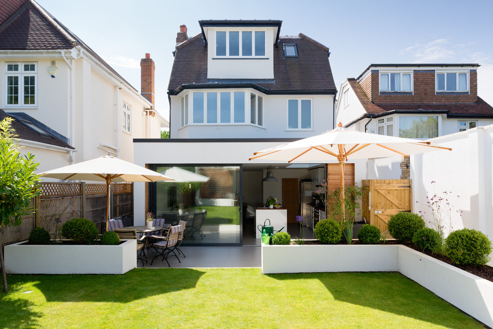 Example of a trendy white three-story exterior home design in London with a clipped gable roof