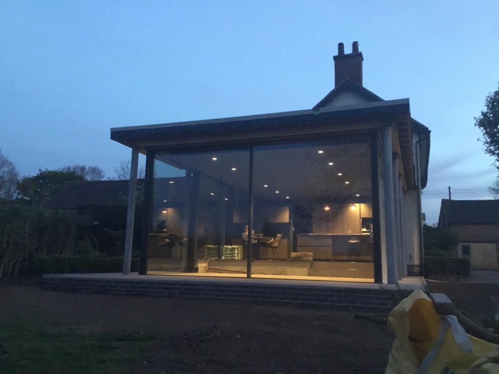 Foto della villa piccola bianca contemporanea a un piano con rivestimento in vetro e tetto piano