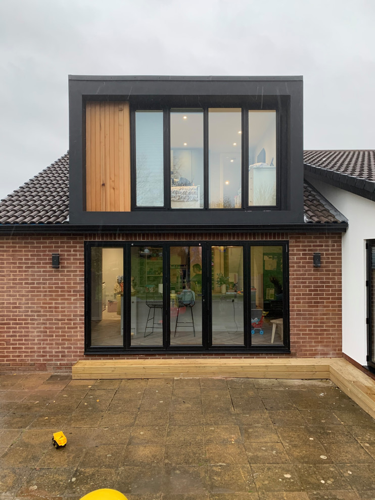 Idées déco pour une petite façade de maison noire contemporaine en stuc à un étage avec un toit plat.