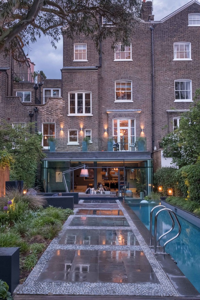 Expansive and brown contemporary brick terraced house in London with three floors and a pitched roof.