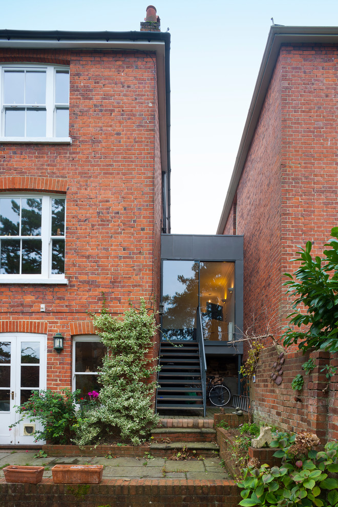 This is an example of a contemporary brick house exterior in Surrey with three floors.