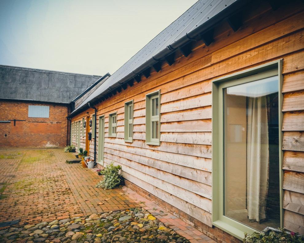 Идея дизайна: маленький, одноэтажный, деревянный, коричневый частный загородный дом в стиле кантри с двускатной крышей и металлической крышей для на участке и в саду