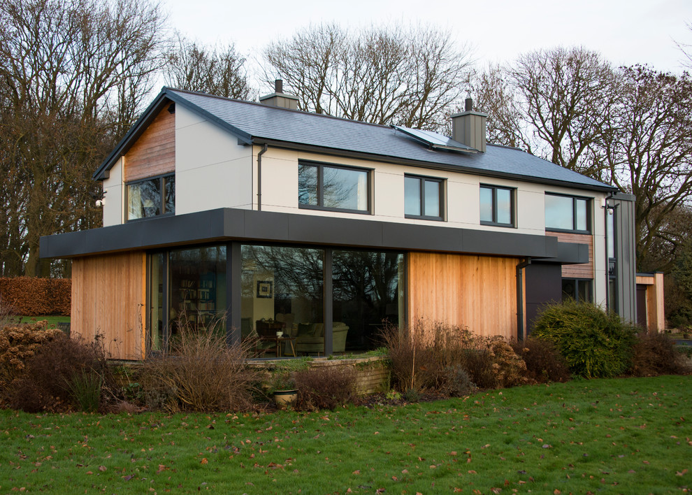 Imagen de fachada de casa multicolor campestre de dos plantas con revestimientos combinados, tejado a dos aguas y tejado de teja de madera