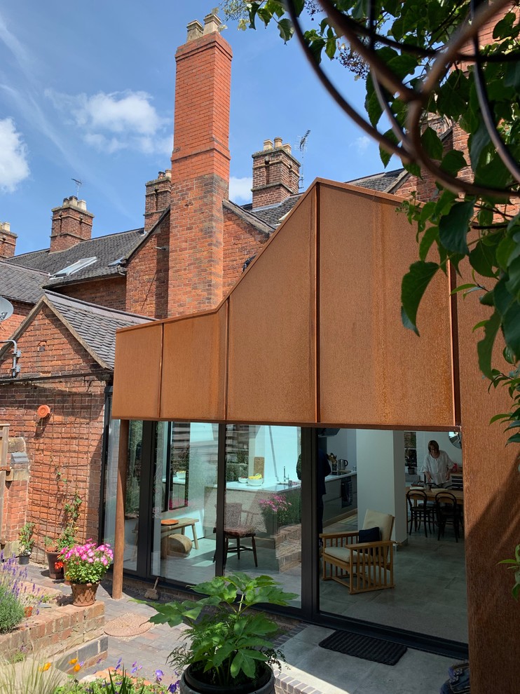 Modelo de fachada de casa pareada marrón contemporánea pequeña de una planta con revestimiento de metal, tejado a dos aguas y tejado de varios materiales