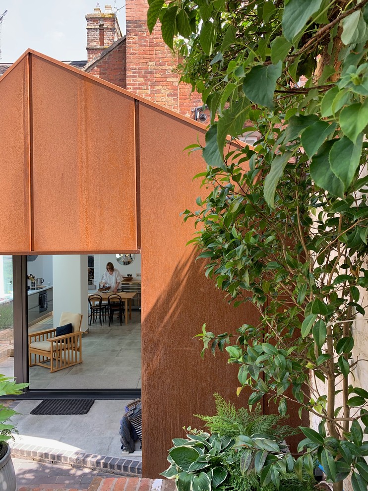 Идея дизайна: маленький, одноэтажный, коричневый таунхаус в современном стиле с облицовкой из металла, двускатной крышей и крышей из смешанных материалов для на участке и в саду
