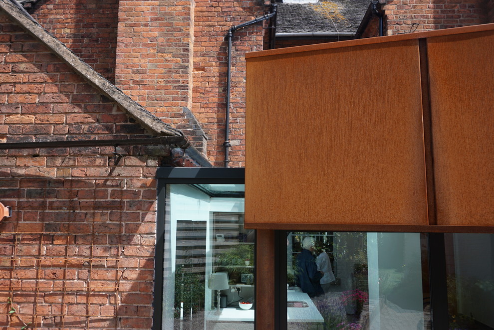 Esempio della facciata di una casa a schiera piccola marrone contemporanea a un piano con rivestimento in metallo, tetto a capanna e copertura mista