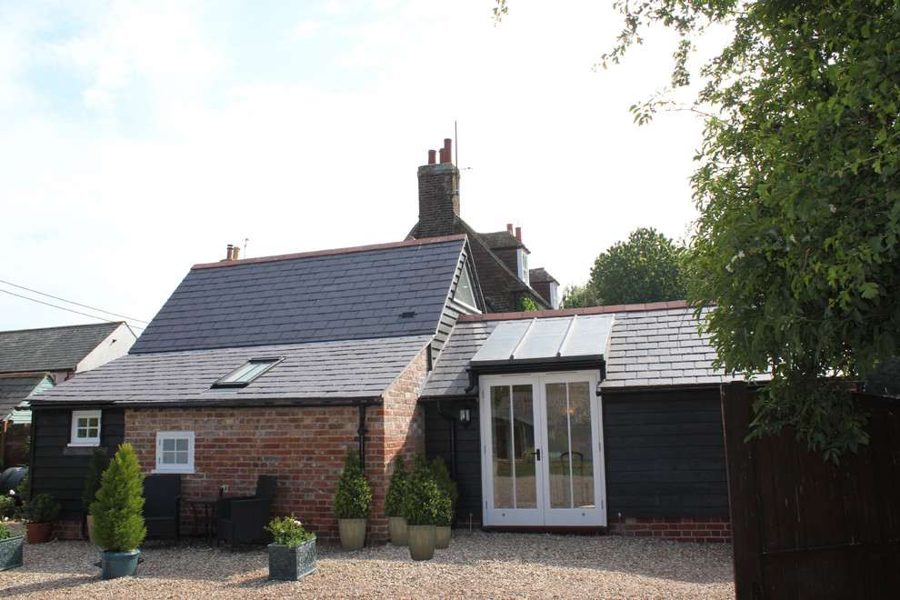 Medium sized and black rustic bungalow detached house in Kent with wood cladding, a pitched roof and a tiled roof.