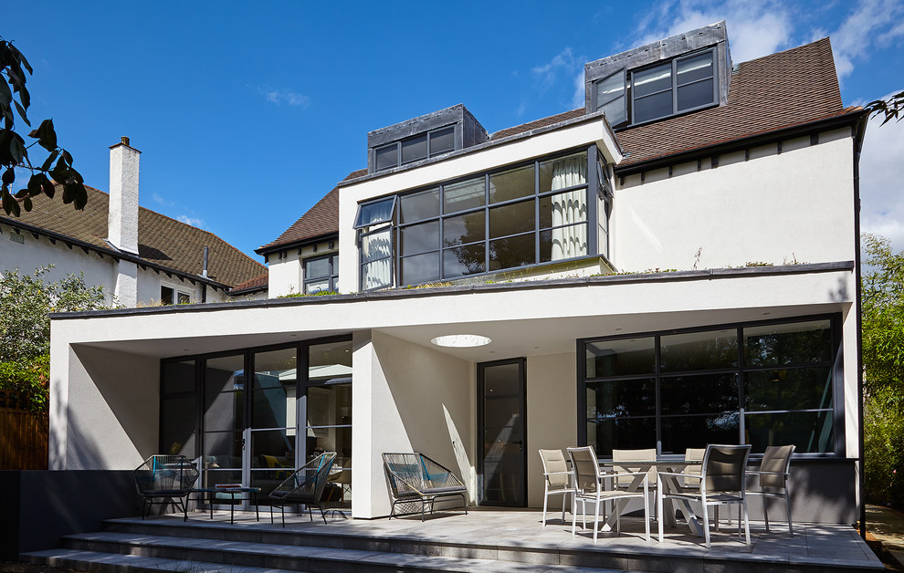 This is an example of a medium sized and white contemporary two floor render detached house in London with a tiled roof.