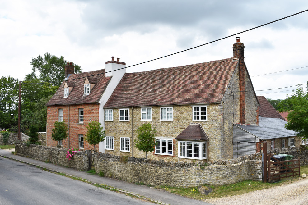 Photo of a brown rural two floor detached house in Wiltshire with stone cladding, a pitched roof and a shingle roof.