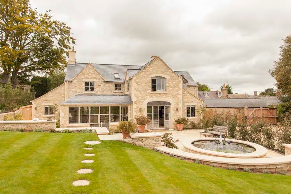 Beige farmhouse two floor house exterior in Gloucestershire with stone cladding and a pitched roof.