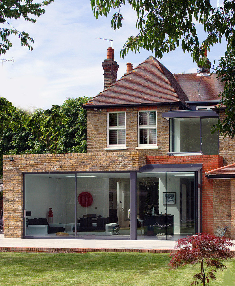 Inspiration pour une façade de maison marron design en brique à un étage avec un toit à quatre pans.