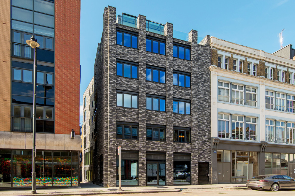 Immagine della facciata di un appartamento grigio industriale a tre piani con rivestimento in mattoni e tetto piano