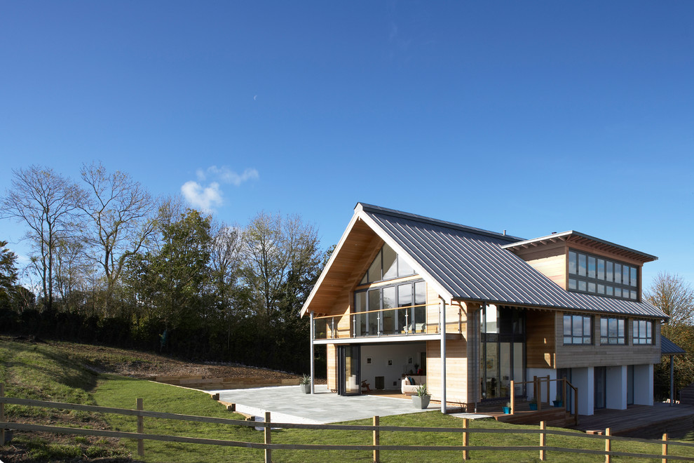 Large and brown rustic split-level house exterior in Dorset with wood cladding and a pitched roof.