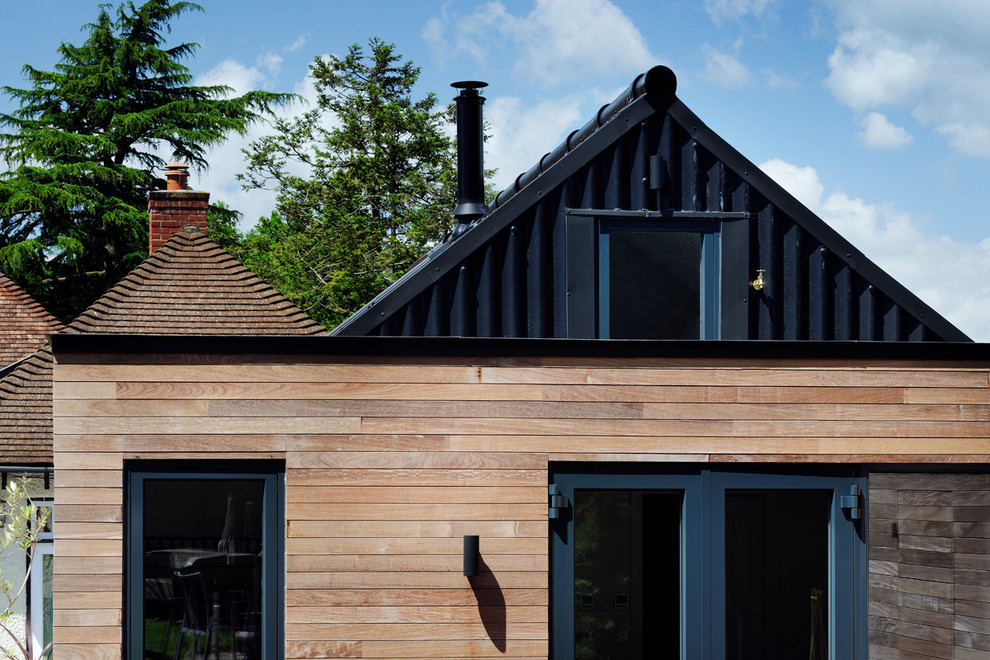 This is an example of a contemporary bungalow house exterior in Hampshire with wood cladding.