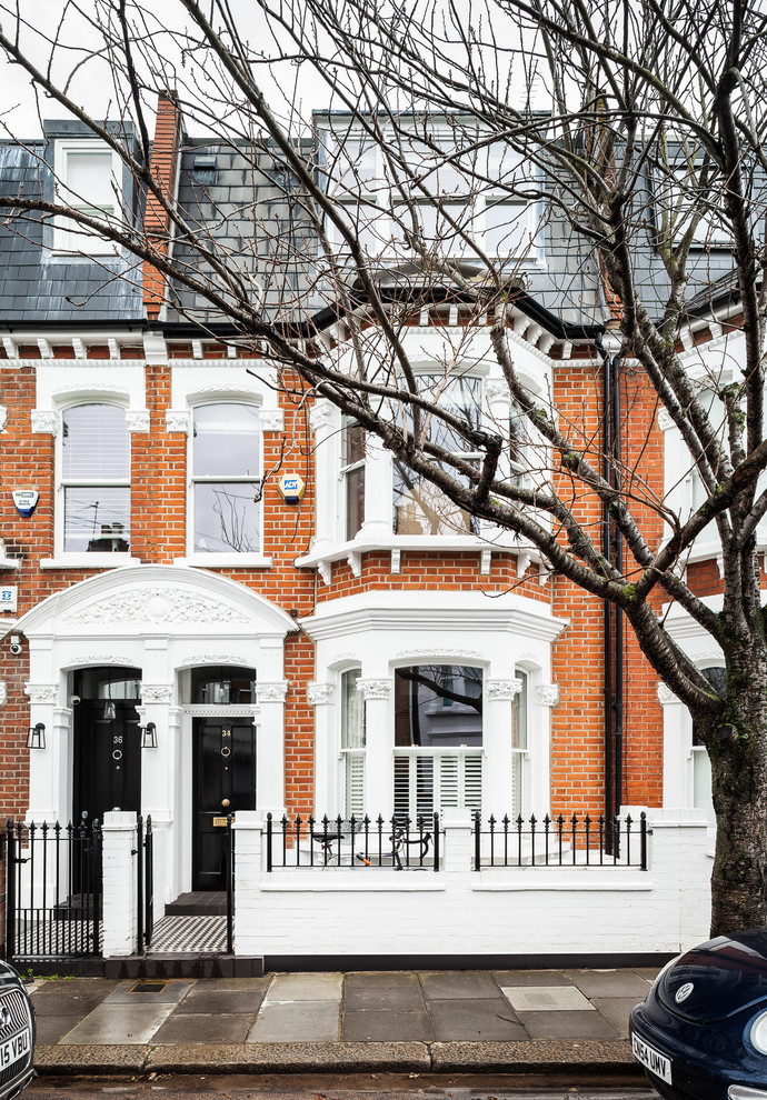 Inspiration for a large and red classic brick house exterior in London with three floors and a mansard roof.