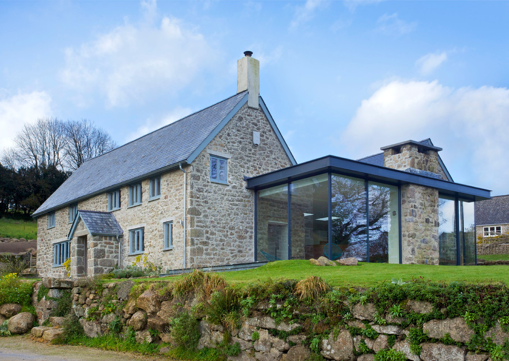 Idée de décoration pour une façade de maison champêtre en pierre à un étage avec un toit à deux pans.