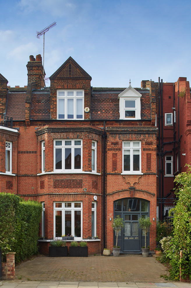 This is an example of a red traditional brick terraced house in London with three floors and a pitched roof.