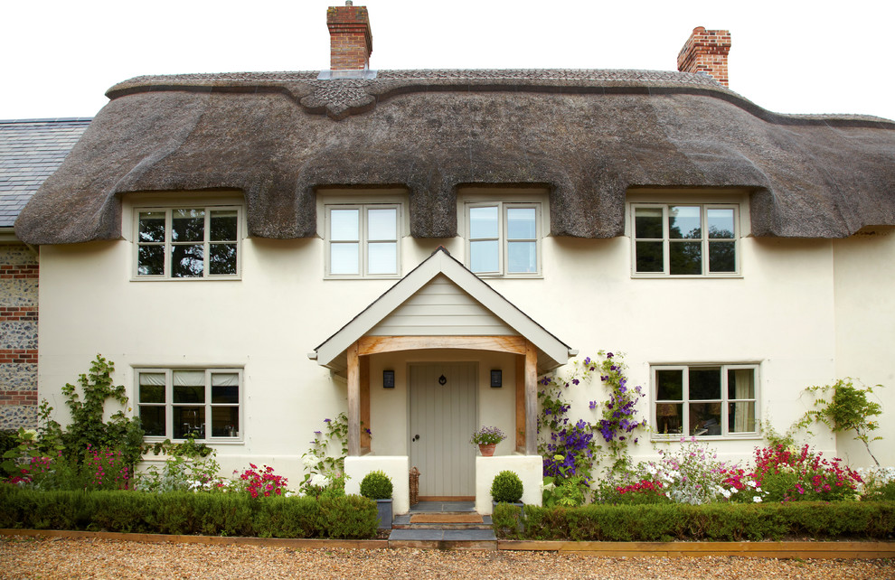 This is an example of a beige farmhouse two floor house exterior in Wiltshire.