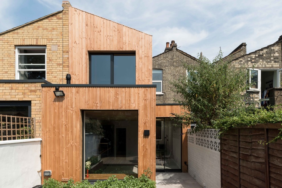 Photo of a medium sized contemporary two floor rear house exterior in London with wood cladding and a lean-to roof.