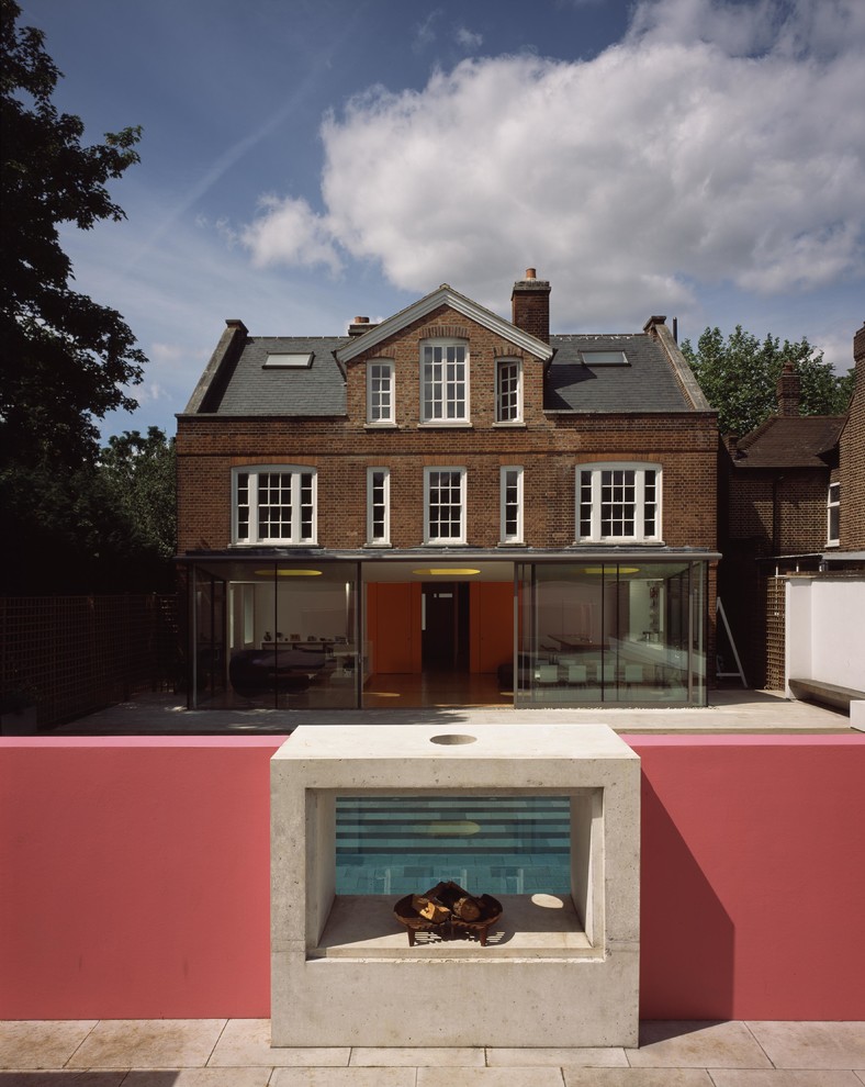 Medium sized and red traditional glass house exterior in London with three floors and a pitched roof.