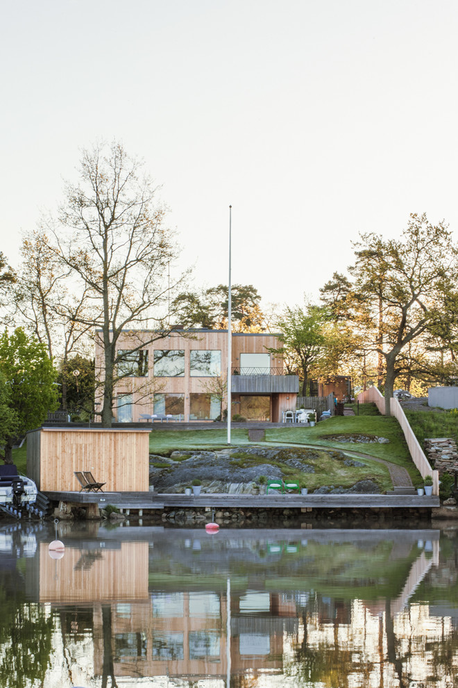 Cette photo montre une façade de maison beige scandinave en bois de taille moyenne et à un étage avec un toit plat.
