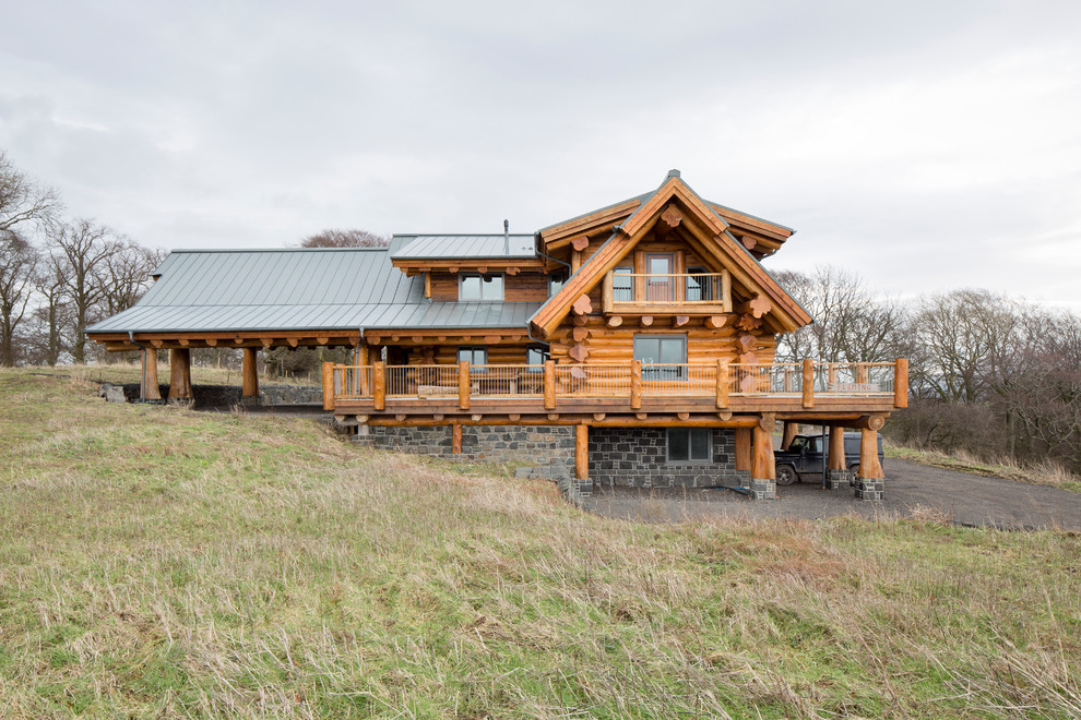 Пример оригинального дизайна: деревянный, коричневый, трехэтажный дом среднего размера, из бревен в стиле рустика с двускатной крышей и металлической крышей