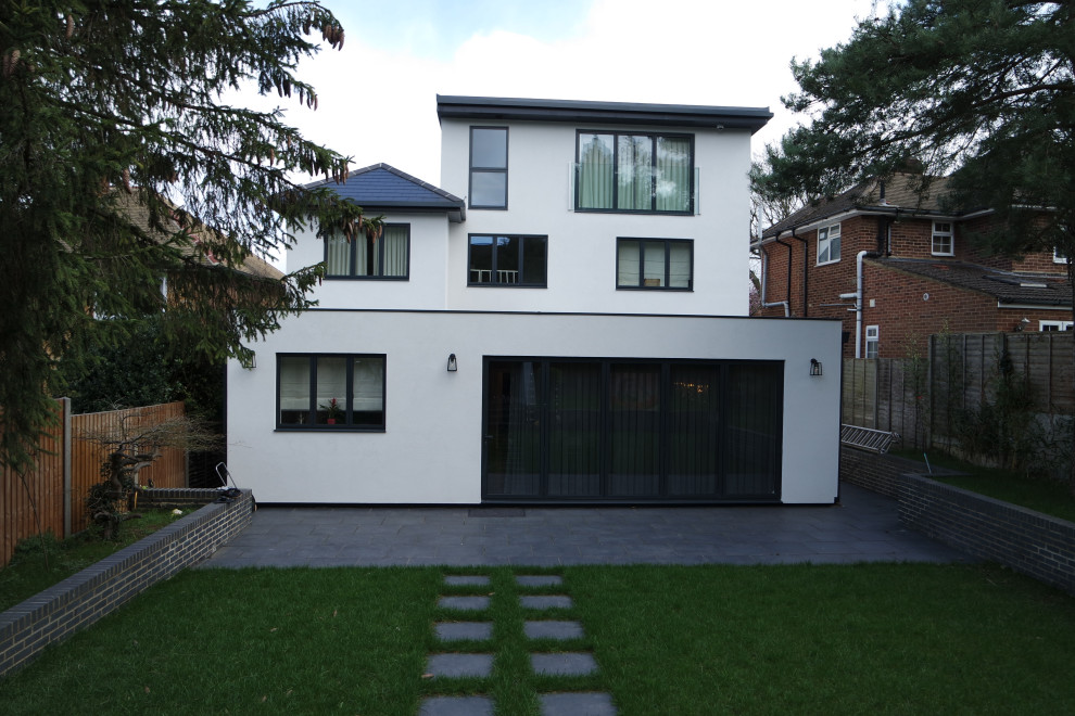 Inspiration for a white modern render detached house in Surrey with three floors, a lean-to roof and a tiled roof.
