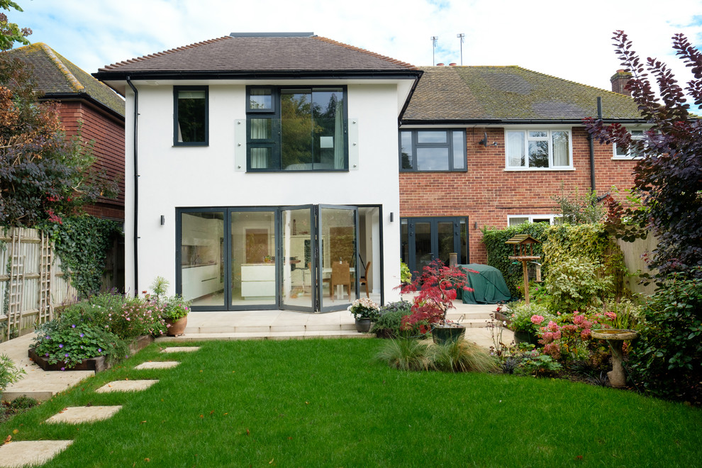 This is an example of a medium sized and white modern two floor semi-detached house in Surrey with a pitched roof and a tiled roof.