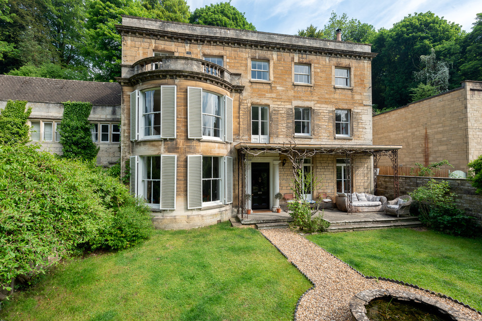This is an example of a large and beige victorian two floor detached house in Gloucestershire with stone cladding, a tiled roof and a flat roof.