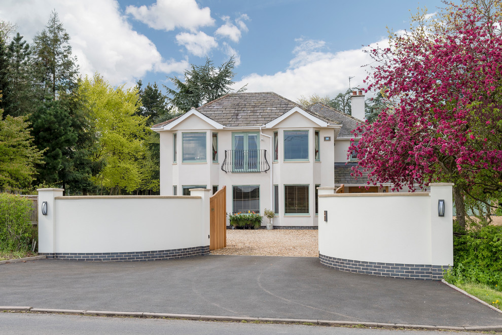 Réalisation d'une grande façade de maison beige minimaliste en stuc à deux étages et plus avec un toit à quatre pans.