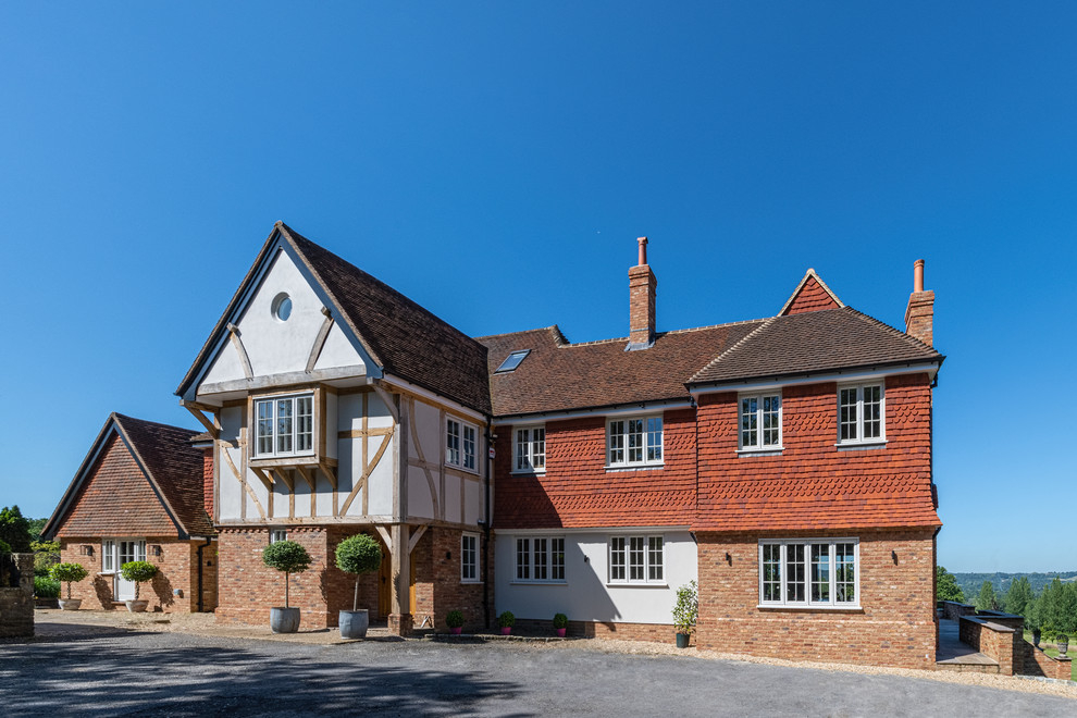 Zweistöckiges Landhaus Einfamilienhaus mit Mix-Fassade, brauner Fassadenfarbe, Walmdach und Schindeldach in Surrey