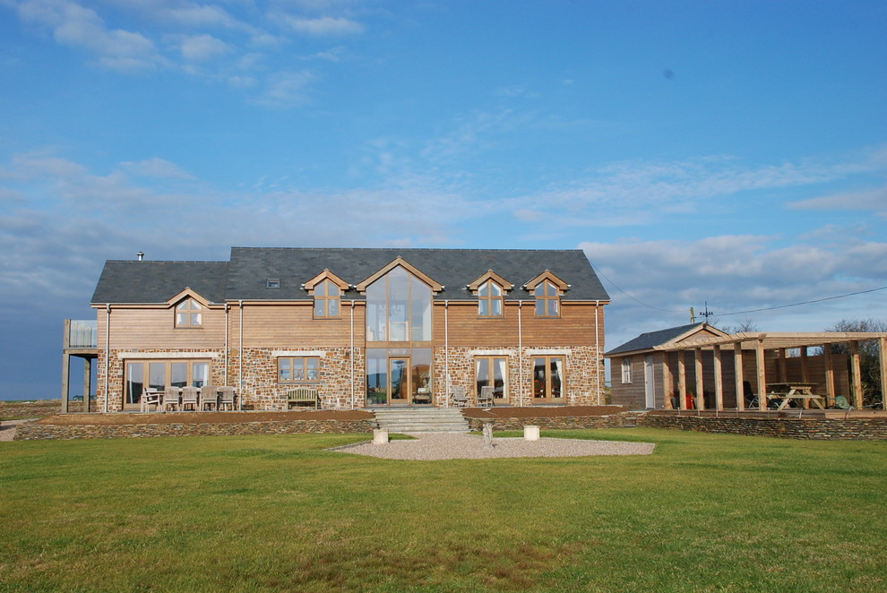 Large trendy two-story stone exterior home photo in Cornwall with a tile roof and a gray roof