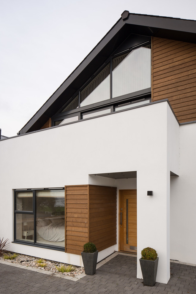 Cette photo montre une façade de maison blanche bord de mer en stuc de taille moyenne et à un étage avec un toit à deux pans.