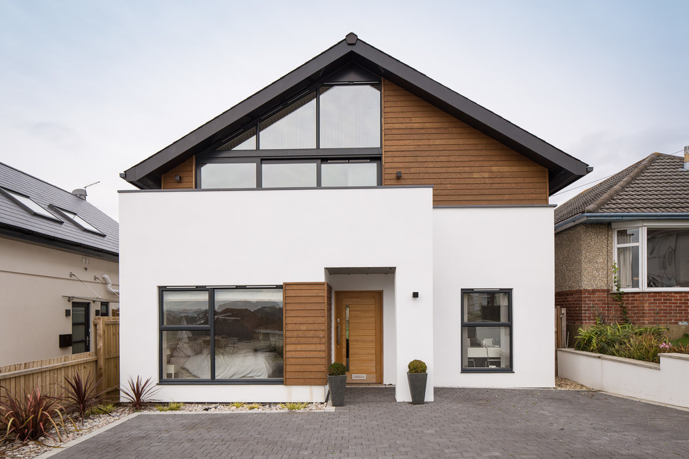 This is an example of a medium sized and white beach style two floor render house exterior in London with a pitched roof.