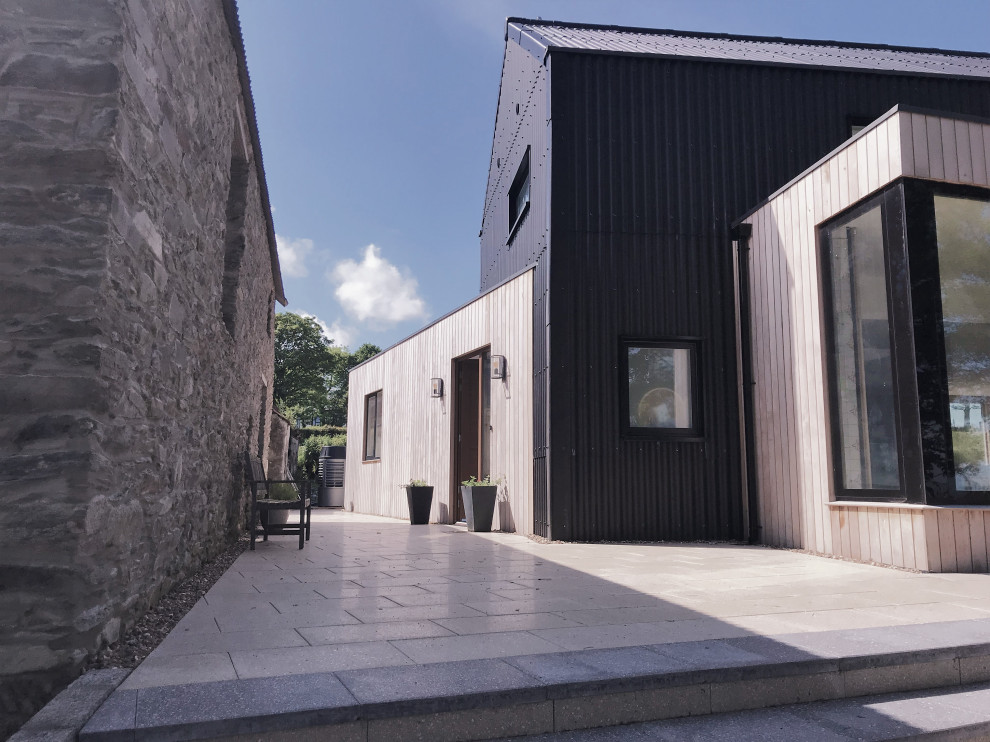 Réalisation d'une façade de maison métallique et noire design de taille moyenne et à un étage avec un toit à deux pans et un toit en métal.