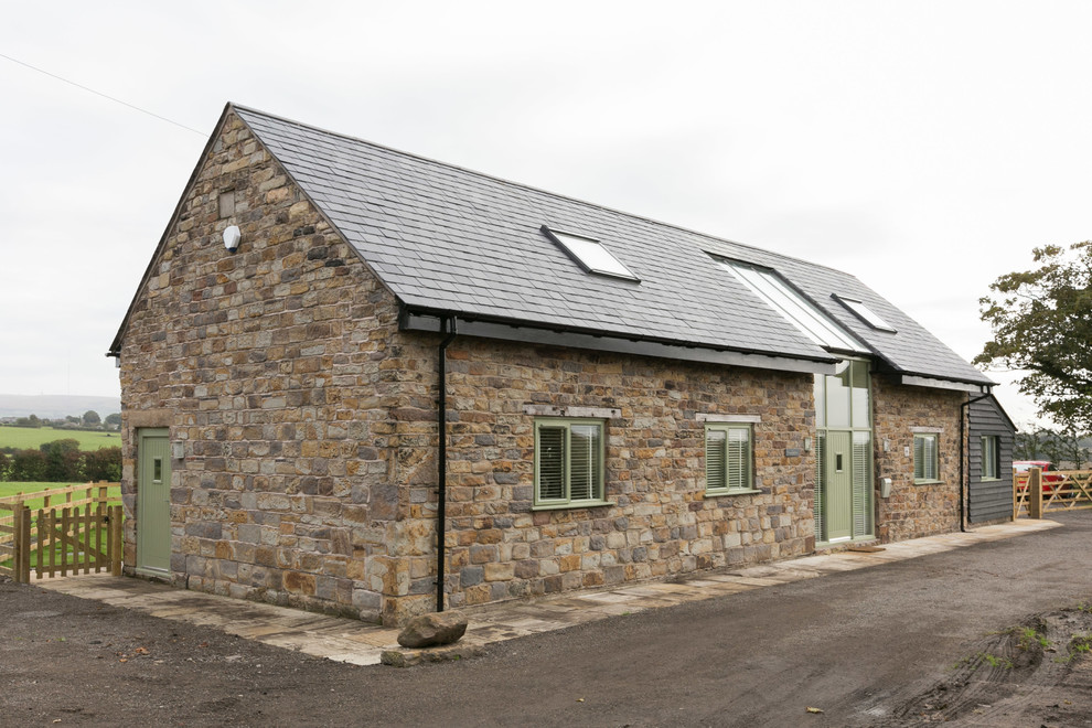 Réalisation d'une façade de grange rénovée champêtre en pierre de taille moyenne et à un étage avec un toit à deux pans.