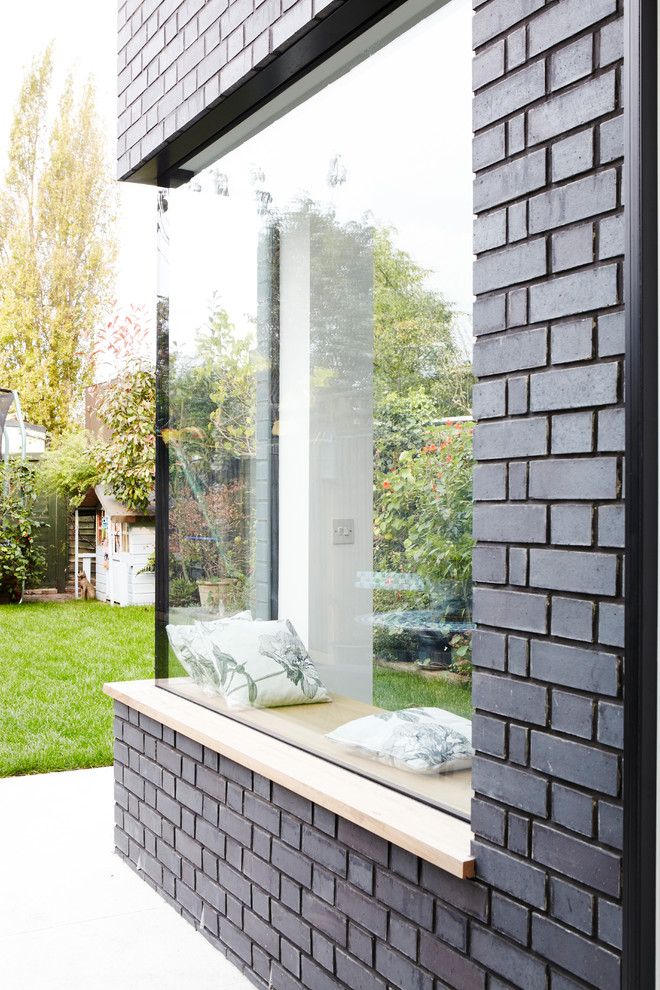 Réalisation d'une façade de maison grise minimaliste en brique.