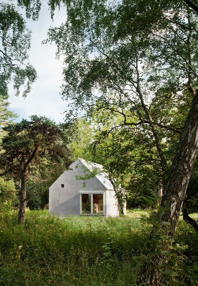 Diseño de fachada gris escandinava pequeña de dos plantas con revestimiento de hormigón y tejado a dos aguas